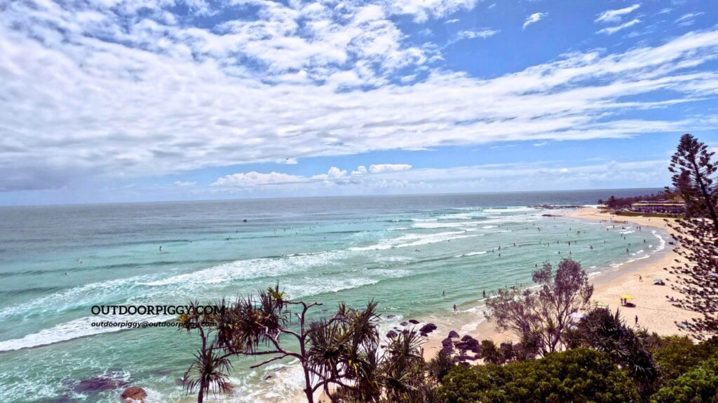 Rainbow Bay with many surfers seen from Coolangatta Rainbow Hill